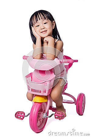 Asian chinese little girl riding a toy tricycle Stock Photo