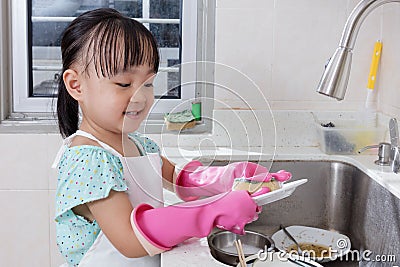 Asian Chinese little girl washing dishes in the kitchen Stock Photo