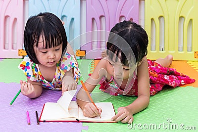 Asian Chinese little sisters laying on the floor coloring Stock Photo