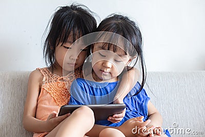 Asian Chinese little sisters using tablet on the sofa Stock Photo
