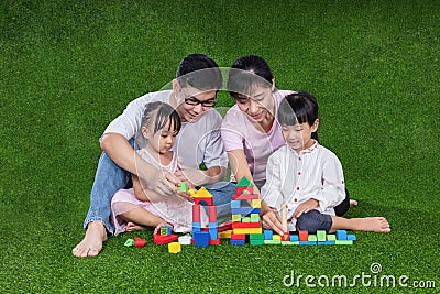 Asian Chinese parents and daughters playing blocks on the grass Stock Photo