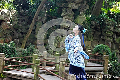 Asian Chinese woman in traditional Blue and white Hanfu dress, play in a famous garden on crooked Bridge Stock Photo