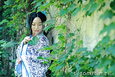 Asian Chinese woman in traditional Blue and white Hanfu dress, play in a famous garden near wall Stock Photo