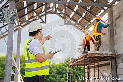 Asian Civil Engineers are working with construction workers who are laying bricks at the construction site Stock Photo