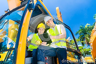 Asian construction driver discussing with engineer blueprints Stock Photo