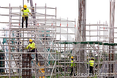 asian construction workers working on scaffolding of building construction site in city. urban expansion in capital city of asia Editorial Stock Photo