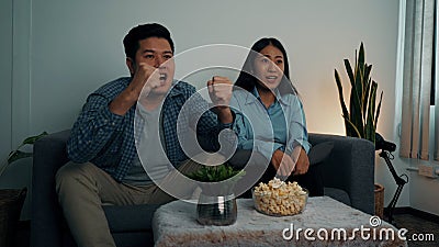 Asian couple has fun cheering on the soccer team competing on TV Stock Photo