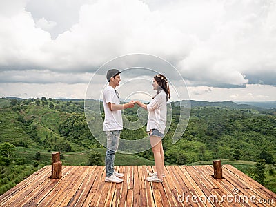 Asian couple holding hands on wooden balcony with mountain view. Mariage proposal concept. terrace for camping tent with landscape Stock Photo