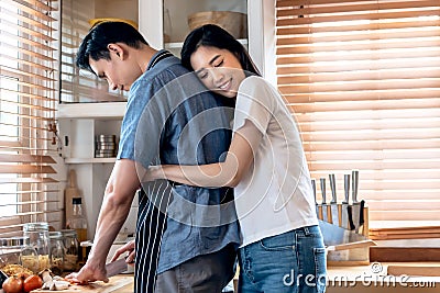 Asian couple in the kitchen, Attractive wife is embracing husband Stock Photo