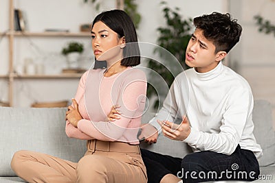 Asian Couple After Quarrel, Husband Talk To Offended Wife Indoor Stock Photo