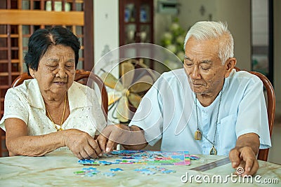Asian couple senior playing with a jigsaw puzzle Stock Photo