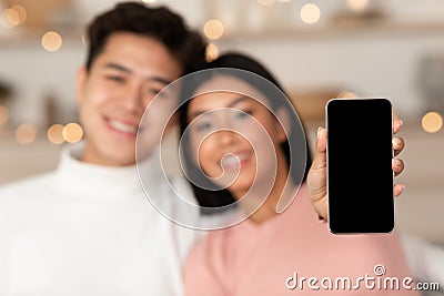 Asian Couple Showing Empty Phone Screen Advertising Mobile Application Indoor Stock Photo