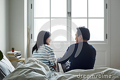 Asian couple talking together in bed Stock Photo