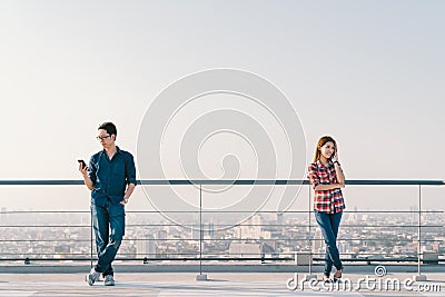 Asian couple using telephone call and smartphone together on building roof. Mobile cellphone device or information technology Stock Photo