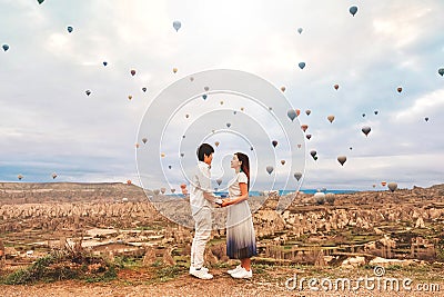 Asian couple watching colorful hot air balloons flying over the valley at Cappadocia, Turkey This Romantic time of love Stock Photo