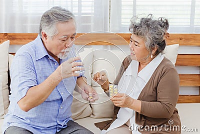 Asian couple woman caring sick old man by giving pill or drug at home Stock Photo