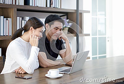 Asian couples spend time together in the living room. Both had a serious expression on their faces after seeing a quote for a home Stock Photo