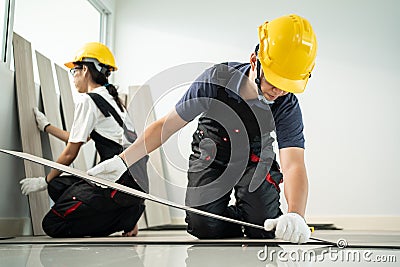 Asian Craftsman worker people installs laminate board on floor at home. Attractive Joiner and Carpenter check and count parquet to Stock Photo