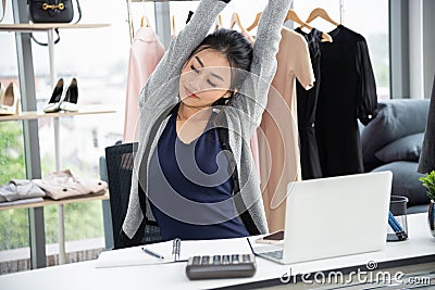 Asian creative designer stretching arms and close eye in front of laptop computer on work desk Stock Photo