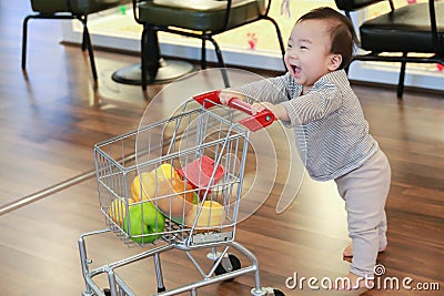 Asian cute baby pushing shopping trolley toy Stock Photo