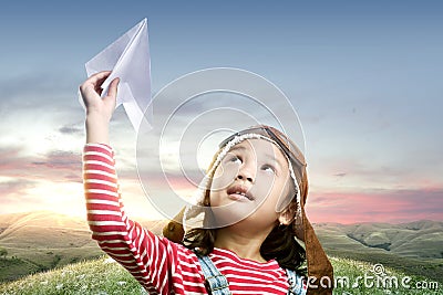 Asian cute girl in an aviator cap with a paper plane with a sunset sky background Stock Photo