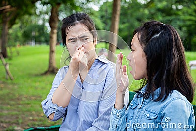 Asian daughter child girl checking breath with her hand,teenager girl horrible bad breath,foul mouth,mother closing her nose,very Stock Photo