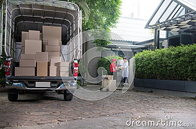 Asian delivery man in red uniform delivering parcel boxes to woman recipient at home Stock Photo