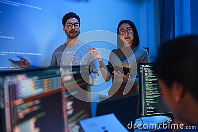 asian developer leads present code review session, pointing at code projected on the wall with colleagues teamwork and knowledge Stock Photo