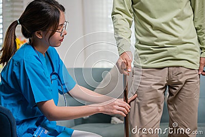 Asian doctor asking and explanation elderly man about pain symptom with walking stick Stock Photo