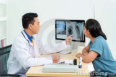 Asian doctor man medical diagnosis of lungs and reported bad news for cancer. Patient listening x-ray scan results from doctor at Stock Photo