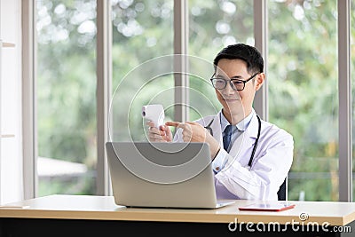 Doctor present and talking about scan head thermometer with patient or customer through online video chat with computer in Stock Photo