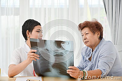 Asian doctor and senior patient looking at xray film together.. Stock Photo