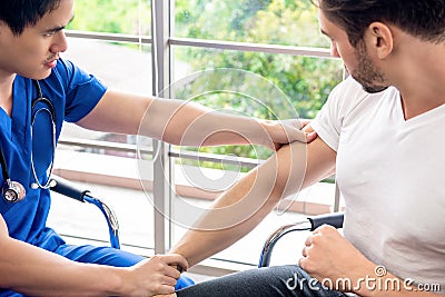 Asian doctor therapist massaging arm of athlete male patient Stock Photo