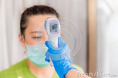 Asian doctor using infrared forehead thermometer gun checking of woman wear mask Stock Photo