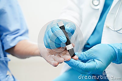 Asian doctor using lancet pen on senior patient finger for check sample blood sugar level to treatment diabetes Stock Photo