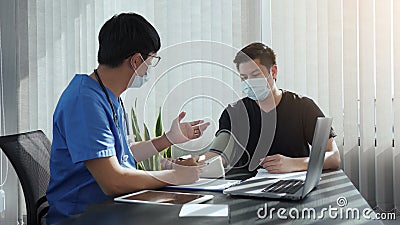 Asian doctor is using a patient`s blood pressure monitor at the time of his annual check-up and explains his blood pressure Stock Photo