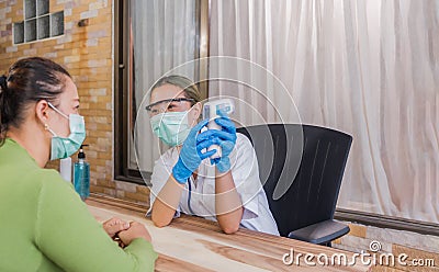 Asian doctor woman wear protective mask and glasses, stethoscope using infrared forehead thermometer Stock Photo