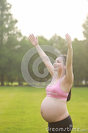 Asian Eastern Chinese happy beautiful pregnant woman hug embrace nature in green forest outdoor full of hope enjoy positive life Stock Photo