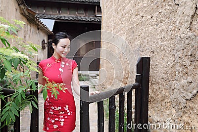 Asian Eastern oriental Chinese woman beauty in traditional ancient dress costume red cheongsam in ancient town garden fence Stock Photo