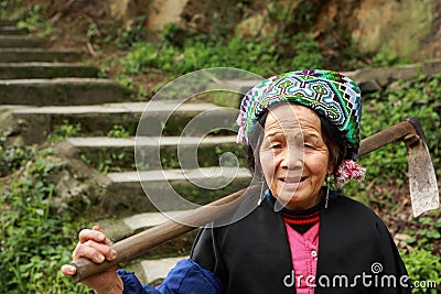 Asian elderly Chinese woman farmer peasant with hoe on shoulder. Editorial Stock Photo