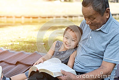 Asian elderly having faith to the Lord, God reading bible outdoor with kid Stock Photo