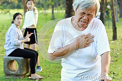 Asian elderly people having heartbeats fast,difficulty breathing,symptoms of heart problem while walking exercise in outdoor park, Stock Photo