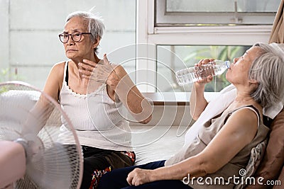 Asian elderly people who are hot and thirsty from high temperature heat waves,drinking water help to reduce body heat,prevent heat Stock Photo