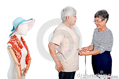 Asian elderly tailor woman show action of body measurement for the other elderly customer near cloth puppet. Image is isolated on Stock Photo