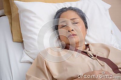 Asian elderly woman asleep on bed with surveillance in hospital ward, patient senior unconscious lying on bed. Stock Photo