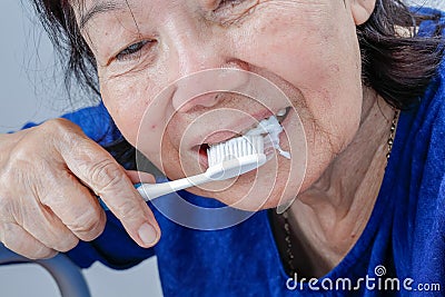 Asian elderly woman trying use toothbrush ,hand tremor. Stock Photo