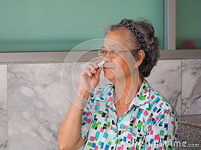 Asian elderly woman using herbal inhaler Stock Photo
