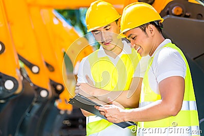 Asian engineer discussing plans on construction site Stock Photo