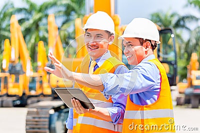 Asian engineer discussing plans on construction site Stock Photo