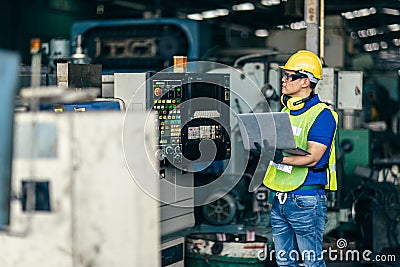 Asian engineer programming the machine in factory with laptop computer to setup program process Stock Photo